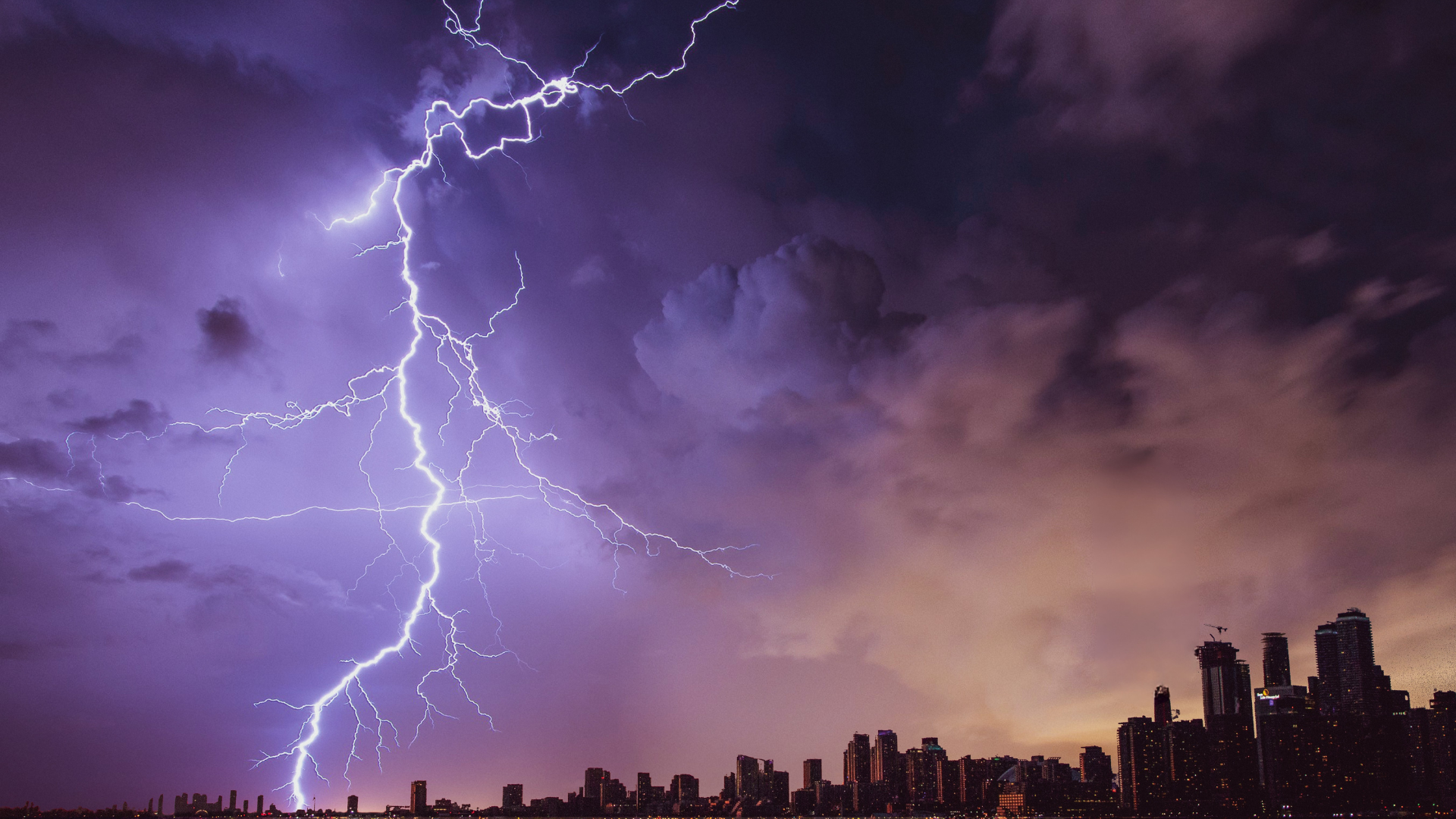 Lightning over city skyline representing hurricane season preparation by South Florida builders and KW PROPERTY MANAGEMENT & CONSULTING